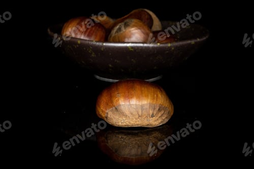 Preview: Lot Of Whole Edible Brown Chestnut One In Focus In Glazed Bowl Isolated On Black Glass