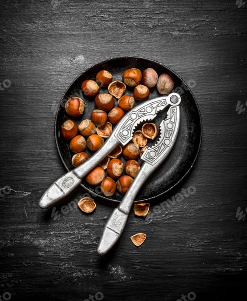 Preview: Hazelnuts With Nutcracker On The Old Plate. On The Black Wooden Table.