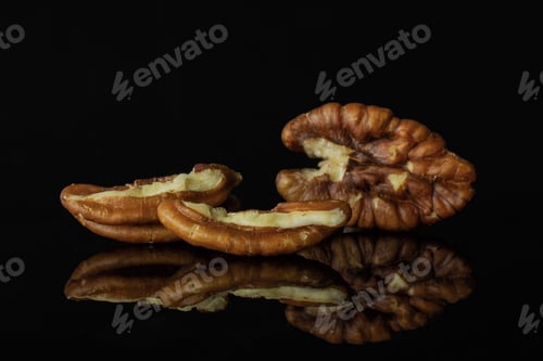 Preview: Group Of One Whole Two Halves Of Unshelled Fresh Brown Pecan Nut Half Isolated On Black Glass