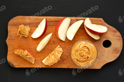 Preview: Raw Red Apples And Peanut Butter On A Rustic Wooden Board On A Black Background, Top View. Flat