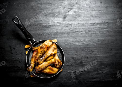 Preview: Fried Chicken Legs In A Frying Pan. On A Black Wooden Background.