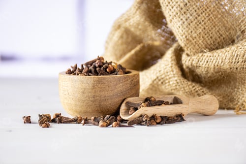 Preview: Lot Of Whole Small Dried Cloves Spice Scoop And Textil With Wooden Bowl With Red Flowers On White