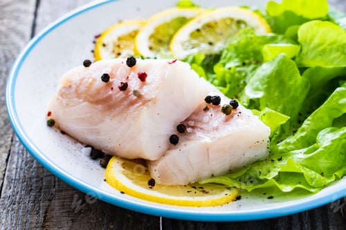 Preview: Fresh Raw Cod With Vegetable Leaves And Lemon On Wooden Table