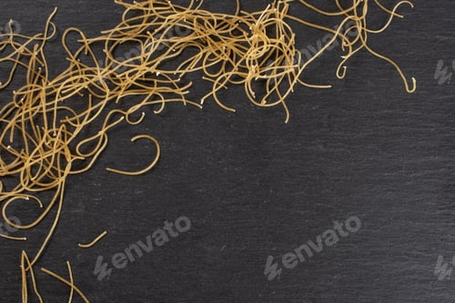 Preview: Lot Of Pieces Of Thin Raw Pasta Noodles Copyspace Flatlay On Grey Stone