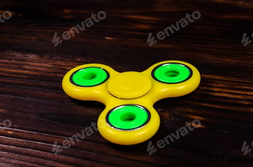 Preview: Yellow Fidget Spinner On Rustic Wooden Desk