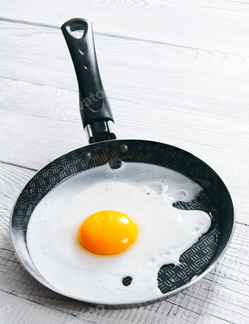 Preview: Fried Egg In A Frying Pan. On A Wooden Background.