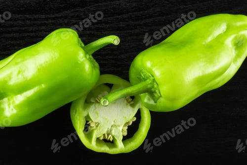 Preview: Group Of Two Whole One Slice Of Light Green Bell Pepper Flatlay Isolated On Black Wood