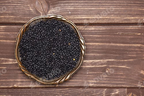 Preview: Lot Of Whole Black Lentils Beluga Variety In Old Iron Bowl Flatlay On Brown Wood