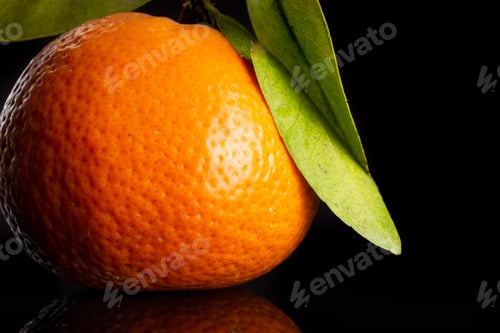Preview: Macro Closeup Of One Whole Fresh Orange Mandarine With Green Leaves Isolated On Black Glass