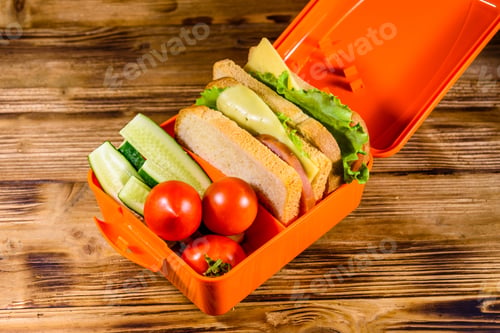 Preview: Lunch Box With Sandwiches, Cucumbers And Tomatoes On Rustic Wooden Table