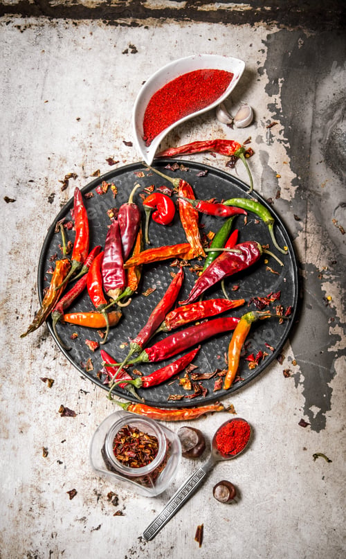 Preview: Dried Chili Peppers On A Tray With Crushed Red Pepper In The Cups, With Herbs. On Rustic