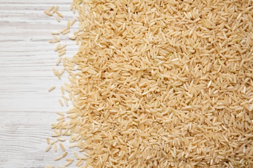 Preview: Dry Brown Rice On A White Wooden Background, Top View. Overhead, From Above, Flat Lay. Space For