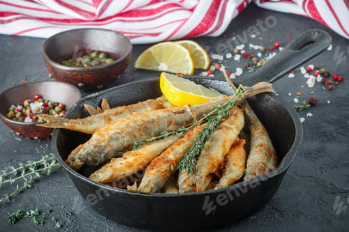 Preview: Fried Smelt In A Frying Pan On The Table With Lemon, Thyme, Capers, Spices And Red Onion. Small Fish