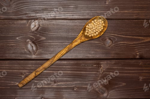 Preview: Lot Of Whole Raw Chickpeas Kabuli Variety With Olivewood Spoon Flatlay On Brown Wood