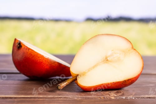 Preview: Group Of Two Halves Of Fresh Red Pear With Green Wheat Field