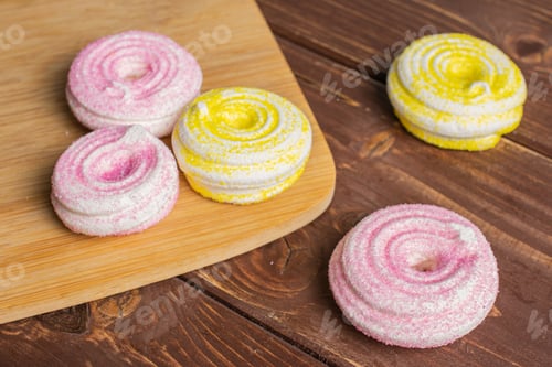 Preview: Group Of Five Whole Pink And Yellow Sweet Meringue On Bamboo Cutting Board On Brown Wood