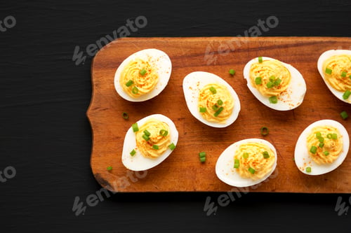 Preview: Homemade Deviled Eggs With Chives On A Rustic Wooden Board On A Black Surface, Top View. Flat Lay
