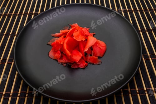 Preview: Pickled Sushi Ginger Slices In Black Plate And Bamboo Mat On Stone Background, Close Up.