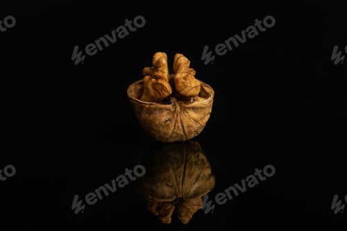 Preview: One Whole Ripe Brown Walnut With Half Shell Isolated On Black Glass