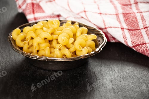 Preview: Lot Of Whole Pasta Cavatappi With A Tea Towel In Old Iron Bowl On Grey Stone