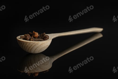 Preview: Lot Of Whole Dry Brown Clove In A Wooden Spoon Isolated On Black Glass