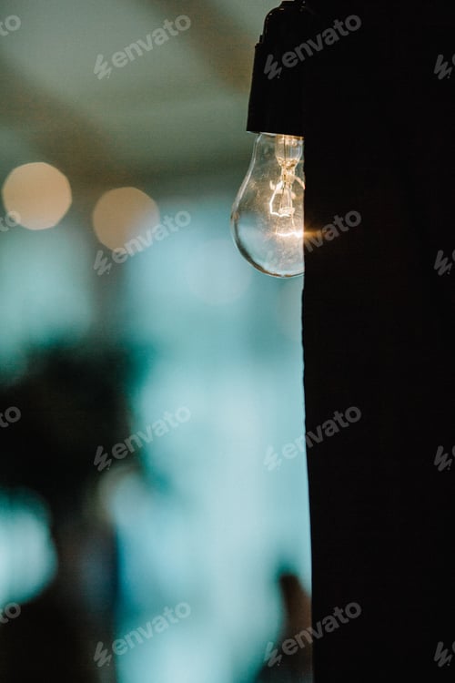 Preview: Illuminated Lightbulb with Defocused Background for Stock