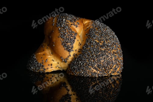 Preview: One Half Of Fresh Twisted Poppy Seed Bun Isolated On Black Glass