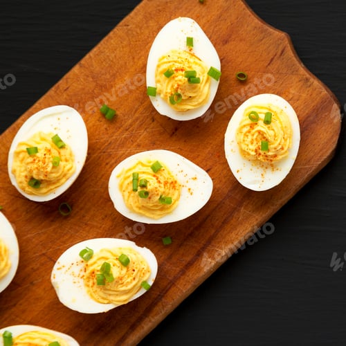 Preview: Homemade Deviled Eggs With Chives On A Rustic Wooden Board On A Black Background, Top View. Flat