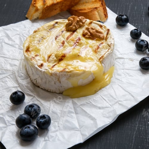 Preview: Grilled Camembert Cheese In Paper With Toasts, Blueberries And Walnuts On A Black Background
