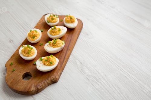 Preview: Homemade Deviled Eggs With Chives On A Rustic Wooden Board On A White Wooden Background, Low Angle
