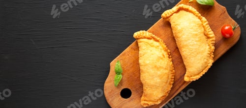 Preview: Homemade Deep Fried Italian Panzerotti Calzone On A Rustic Wooden Board On A Black Surface, Top