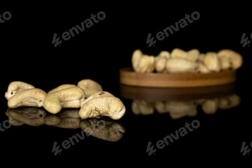 Preview: Lot Of Whole Brown Nut Cashew On Round Bamboo Coaster Isolated On Black Glass