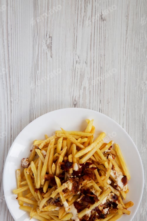 Preview: Tasty Fast Food: French Fries With Cheese Sauce And Bacon On A White Plate Over White Wooden