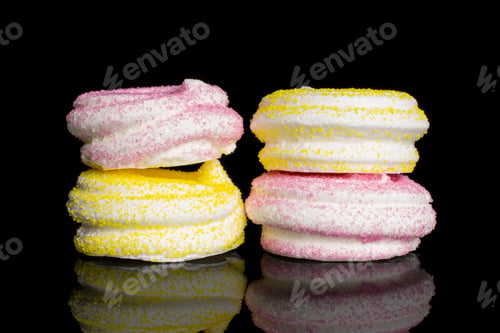Preview: Group Of Four Whole Pink And Yellow Sweet Meringue Isolated On Black Glass