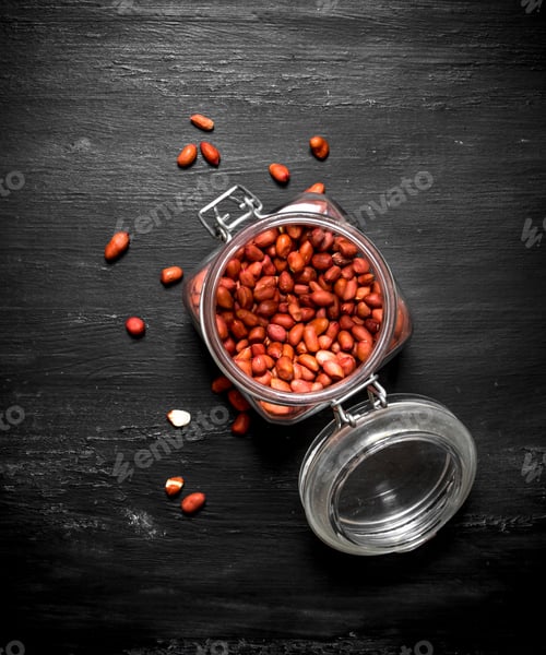 Preview: Shelled Peanuts In A Jar. On The Black Wooden Table.