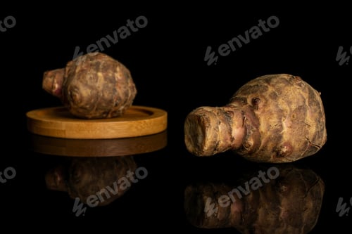 Preview: Group Of Two Whole Fresh Brown Jerusalem Artichoke On Bamboo Coaster Isolated On Black Glass