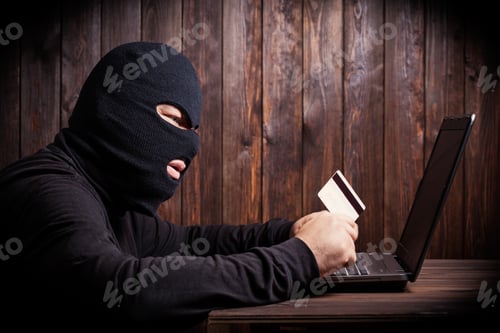 Preview: Hacker Holding A Credit Card On Wooden Background