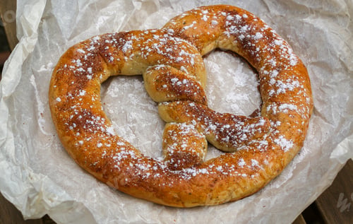 Preview: Cinnamon Sugar Soft Pretzel On A Wooden Table In A Street Cafe. Snack For Tea Or Coffee. Selective