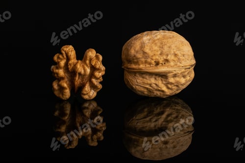 Preview: Group Of Two Whole Ripe Brown Walnut One Is With Shell Isolated On Black Glass