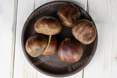 Preview: Group Of Five Whole One Half Of Edible Brown Chestnut With Brown Ceramic Coaster Flatlay On White