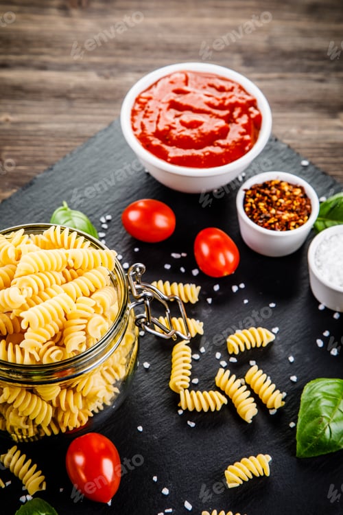 Preview: Raw Pasta With Spices On Black Stone On Wooden Background