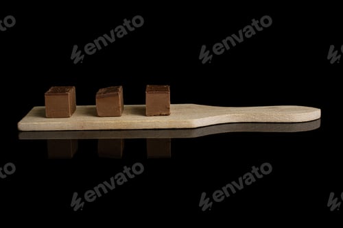Preview: Group Of Three Whole Sweet Brown Viennese Nougat On Small Wooden Cutting Board Isolated On Black