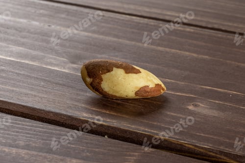 Preview: One Whole Single Unshelled Brazil Nut On Brown Wood