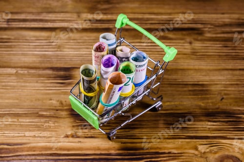 Preview: Many Rolled Up Banknotes In Small Shopping Cart. Euro, American Dollars, Ukrainian Hryvnias