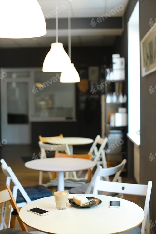 Preview: Empty Snugly Cafe With Cups Of Coffe, Smartphones And Cake On Table. Concept Of Interior And