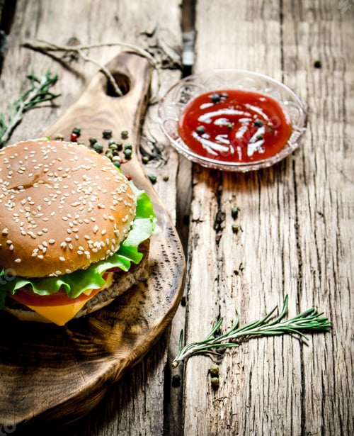 Preview: Tasty Hamburger With Sauce On A Wooden Board. On Wooden Background.