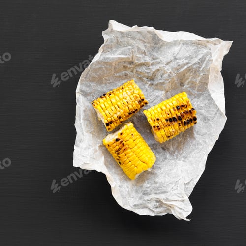 Preview: Grilled Corn On The Cob Over Black Surface, Top View. Summer Food. From Above, Flat Lay.