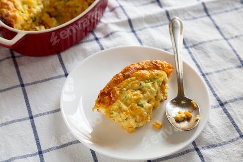 Preview: Homemade Cheddar Corn Pudding Casserole On A White Plate, Low Angle View.