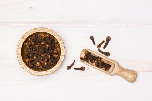 Preview: Lot Of Whole Small Dried Cloves Spice Scoop With Wooden Bowl Flatlay On White Wood