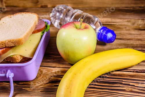 Preview: Ripe Apple, Banana, Bottle Of Water And Lunch Box With Sandwiches On Wooden Table